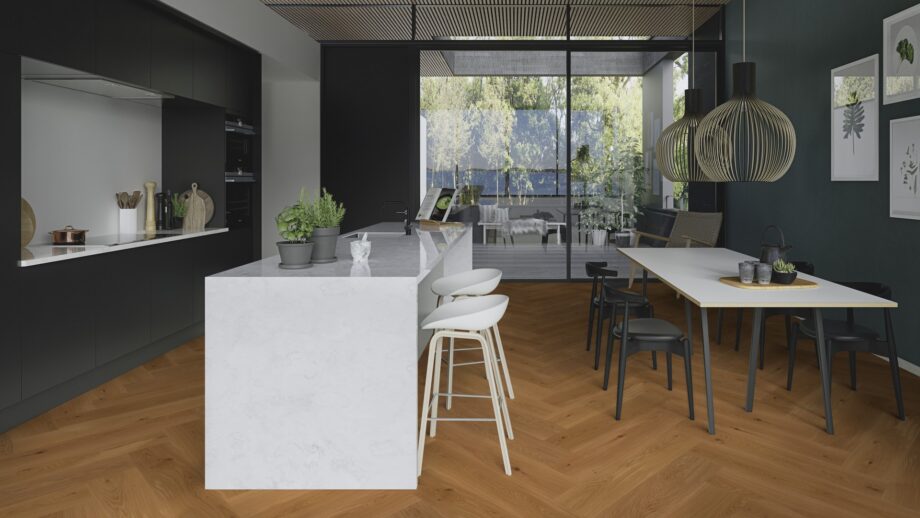 herringbone-flooring-oak-mix-brushed-bevelled-oilwaxed-180mm Herringbone flooring oak mix brushed bevelled oilwaxed 180mm – natural tone and lively grain variation highlighting the character of oak. Installed on a kitchen floor with kitchen furniture, kitchen island, dining table, and a view to the terrace.