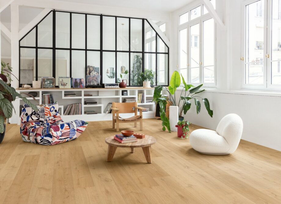 klick-vinyl-quick-step-bloom-elegant-oak-natural Klick Vinyl Quick Step Bloom Elegant Oak Natural im Wohnzimmer verlegt, Sessel, Tisch, Regal und Topfpflanzen.