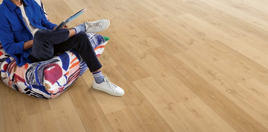 klick-vinylboden-quick-step-bloom-elegant-oak-natural Klick Vinylboden Quick Step Bloom Elegant Oak Natural im Wohnzimmer verlegt, ein Mann sitzt in einem Sessel.