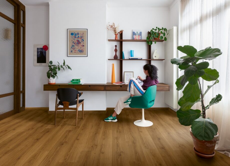 klickvinyl-quick-step-bloom-botanic-caramel-oak Klickvinyl Quick Step Bloom Botanic Caramel Oak im Homeoffice verlegt, eine Frau sitzt am Schreibtisch und arbeitet.