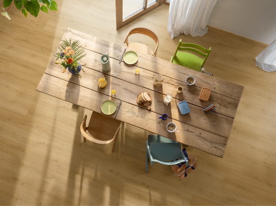 lvt-floors-quick-step-bloom-brushed-oak-honey LVT Floors Quick Step Bloom Brushed Oak Honey installed on a dining room floor. Dining table with breakfast and flowers.