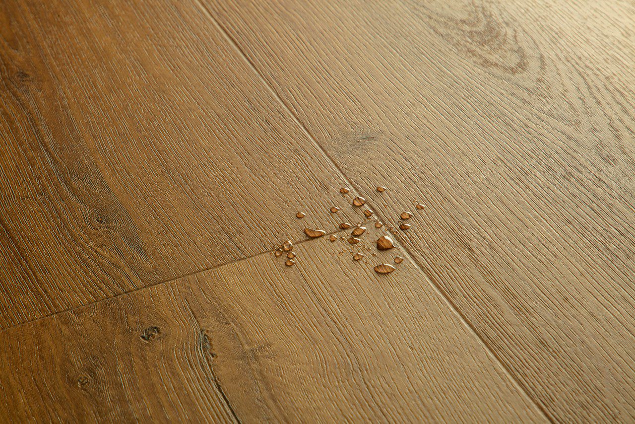 LVT parkett Quick-Step Bloom Botanic caramel oak tooni ja disaini kirjeldus. Veepiisad parketil viitamaks veekindlusele.