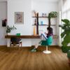 klickvinyl-quick-step-bloom-botanic-caramel-oak Klickvinyl Quick Step Bloom Botanic Caramel Oak im Homeoffice verlegt, eine Frau sitzt am Schreibtisch und arbeitet.