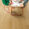 klickvinyl-quick-step-bloom-brushed-oak-honey Klickvinyl Quick Step Bloom Brushed Oak Honey im Kinderzimmer verlegt, Tochter und Vater sitzen am Tisch und zeichnen.