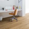 lvt-floor-quick-step-bloom-cotton-oak-natural LVT floor Quick-Step Bloom Cotton Oak Natural installed on a home office floor. White office table, brown leather office stool and a lamp.