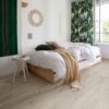 lvt-floor-quick-step-bloom-cotton-oak-white-blush LVT floor Quick-Step Bloom Cotton Oak White Blush installed on a children's room floor. Bed, curtains with green leaf design.