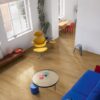 LVT flooring Quick-Step Bloom Cotton Oak Deep Natural installed on a livingroom floor. Blue sofa, sofa table, yellow chair.