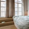 Rigid LVT flooring Quick-Step Bloom Elegant Fumed Oak installed on a bedroom floor. Big bed, Classical design widows from Ceiling to Floor.