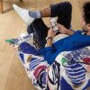 rigid-vinyl-flooring-quick-step-bloom-elegant-oak-natural Rigid Vinyl flooring Quick-Step Bloom Elegant Oak Natural installed on ling room floor, man sitting on a chair and looking phone.