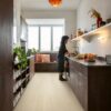 rigid-vinyl-flooring-quick-step-bloom-pure-oak-polar Quick Step Bloom Pure Oak Polar rigid vinyl flooring installed on a kitchen floor, a woman washing vegetables, brown kitchen cabinets.