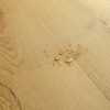 vinuulparkett-quick-step-bloom-brushed-oak-honey Vinüülparkett Quick-Step Bloom Brushed Oak Honey harjatud pind, soe tamme toon, veepiisad vinüülparketil näitamaks veekindlust.