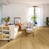 vinyl-flooring-quick-step-bloom-brushed-oak-honey Vinyl flooring Quick-Step Bloom Brushed Oak Honey installed on a Livingroom floor. Sofa, table, shelves.