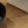 vinyylilattia-quick-step-blos-cocoa-tammi Vinyylilattia Quick Step Blos Cocoa Tammi asennettuna kylpyhuoneen lattialle, tumma kaakaonruskea tammen sävy ja lankkulattia tammi, samansävyiset jalkalistat ja musta luonnonkivinen kylpyamme.