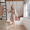 LVT põrand Quick-Step Illume Soft blush paigaldatud koridori põrandale. Naine hommikumantlis hoiab kinni redelist.