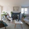 Quick-Step Illume Soft Sky vinyl floor tiles installed on a living room floor – a woman reads a book in a comfortable armchair; a sofa, table and a classic metal fireplace in the room. Light, fresh grey-blue tone with a subtle stone-inspired design.
