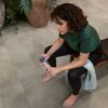vinylboden-beton-quick-step-oro-concrete-rock Frau sitzt auf einer Bank und trinkt Wasser im Home-Gym – der Vinylboden in Betonoptik (Quick-Step Oro Concrete Rock) ist auf dem Boden verlegt.